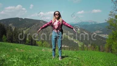 一个年轻的高加索女人带着背包和太阳镜<strong>站在山顶</strong>上举起双手。 概念